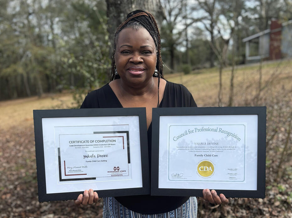 A woman holds two framed certificates.