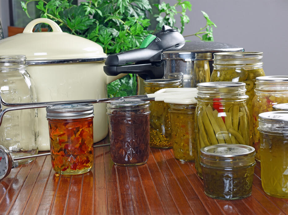 Canning equipment and canned foods sit on a counter.