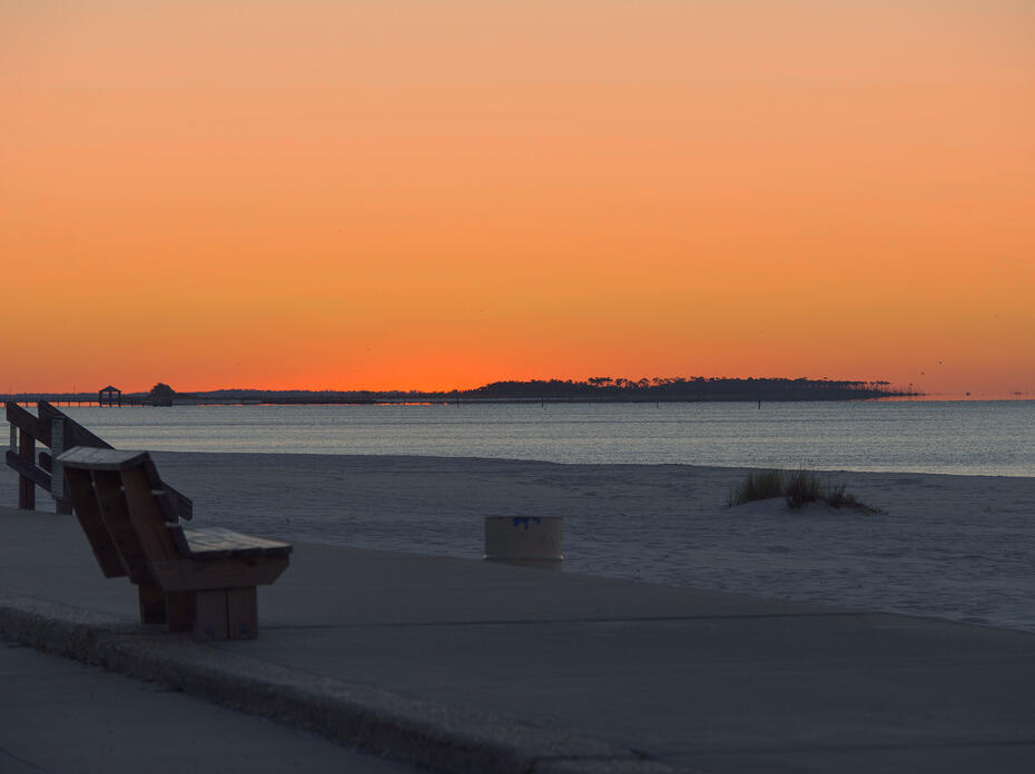 An orange sunset on Biloxi beach with the Gulf of Mexico in the background.