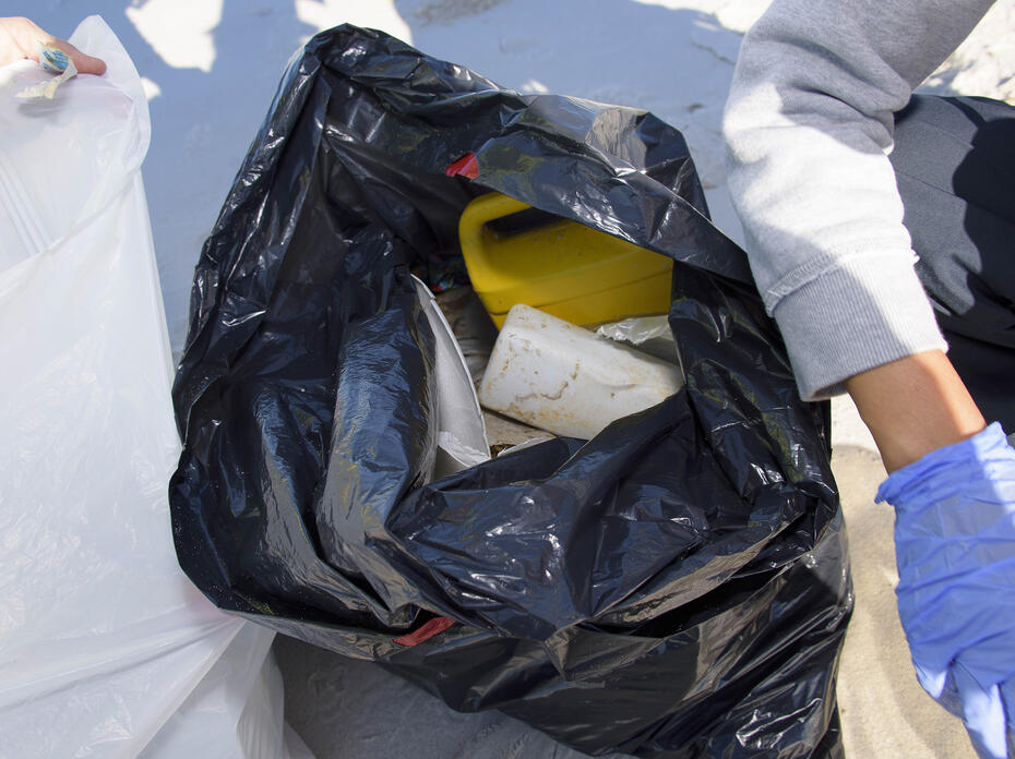 Plastic debris is seen in an open black trash bag sitting on the beach at the 2016 Mississippi Coastal Cleanup.