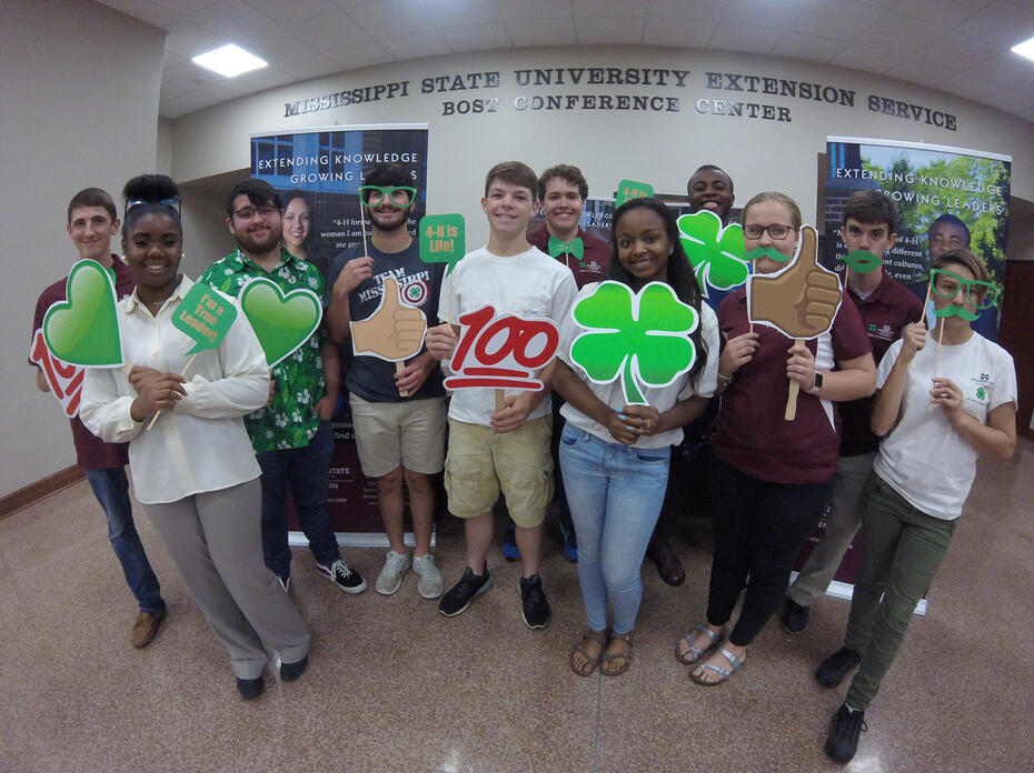 A diverse group of youth displaying 4-H signs.