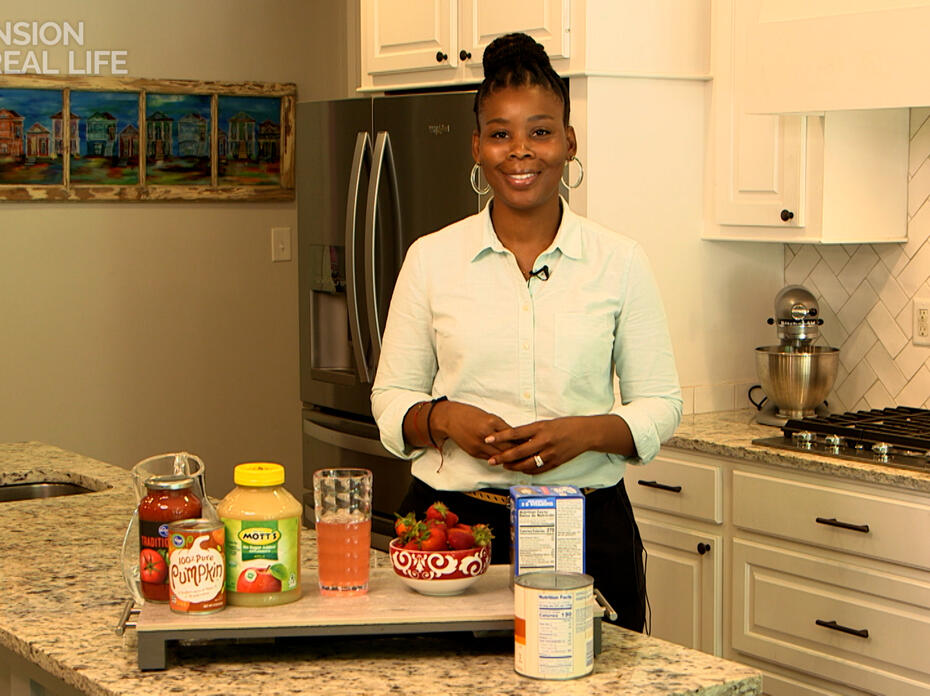 A woman stands in a kitchen with food products on the counter.