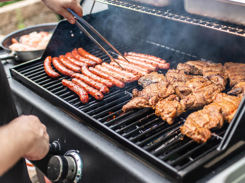 Grill with hotdogs and chicken on it