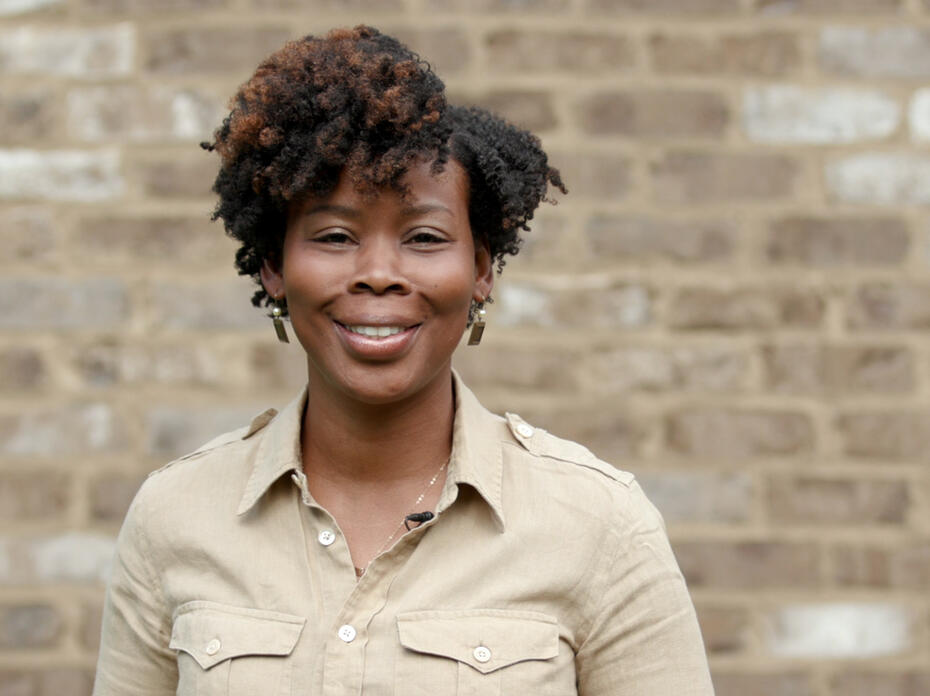 A woman stands in front of a brick wall.