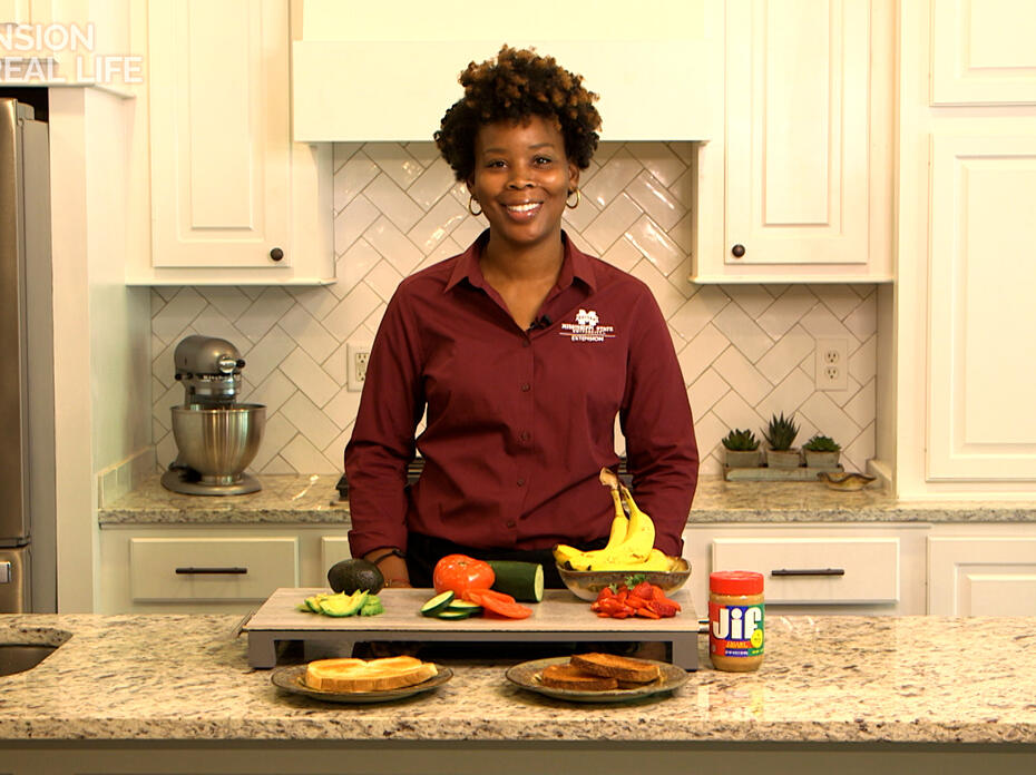 A woman stands behind a kitchen counter of breakfast toast and toppings.