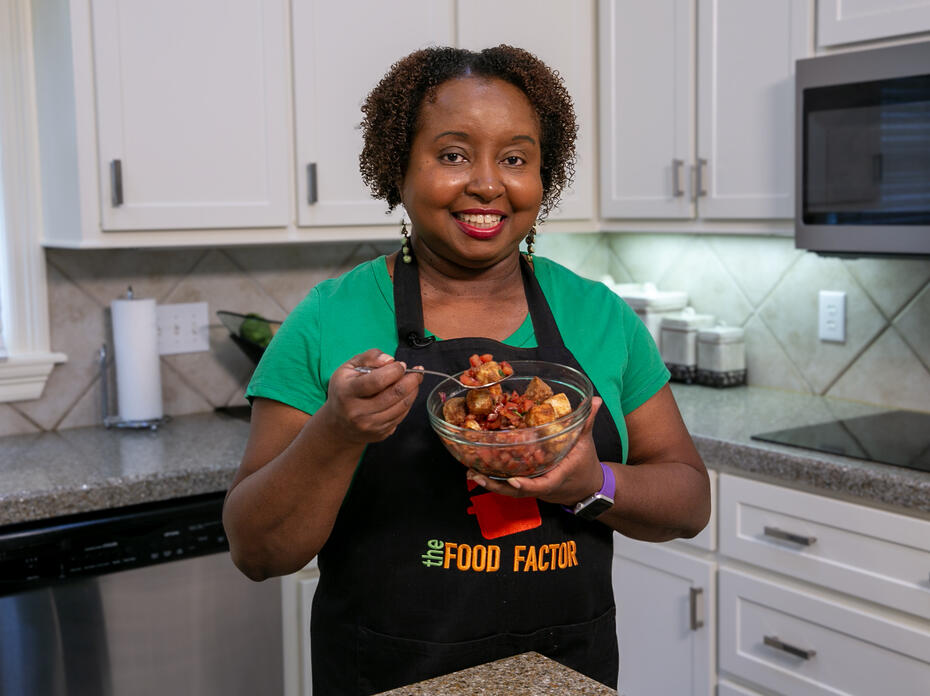 A woman in a kitchen holds a bowl of bruschetta salad.