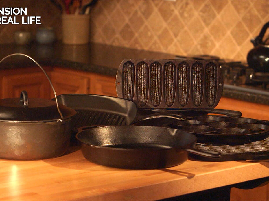 A grouping of various kinds of cast-iron cookware sit on a kitchen counter. 