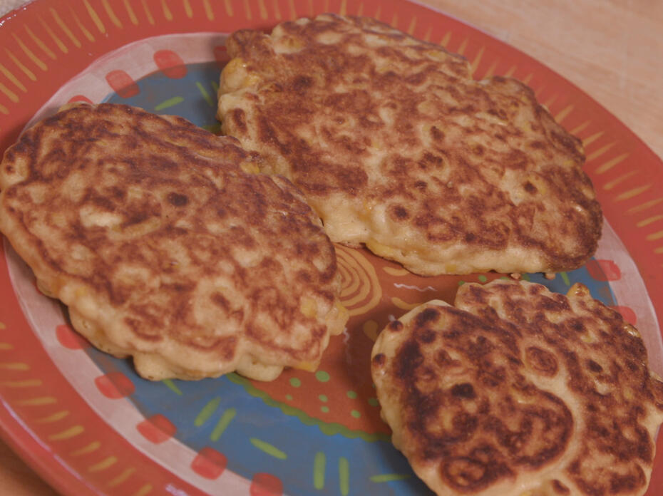Three corn pancakes on a terra cotta plate. 