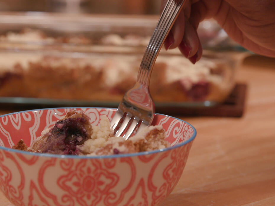 a small bowl with a serving of fruity French toast casserole with a 9x13 pan in the background