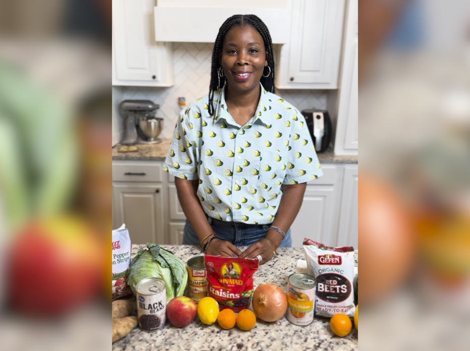 A woman in a kitchen with fruits and vegetables on the counter.