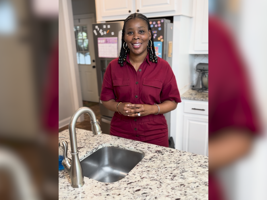 A woman stands at the kitchen sink.