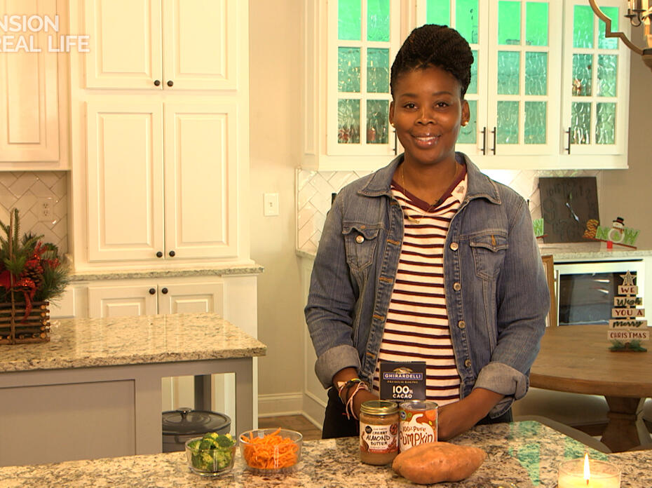 A woman stands at a kitchen counter with ingredients displayed.