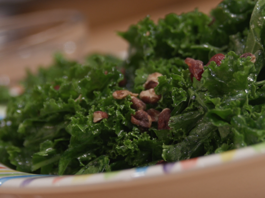 Kale topped with pecans and dried cranberries in a colorful bowl. 