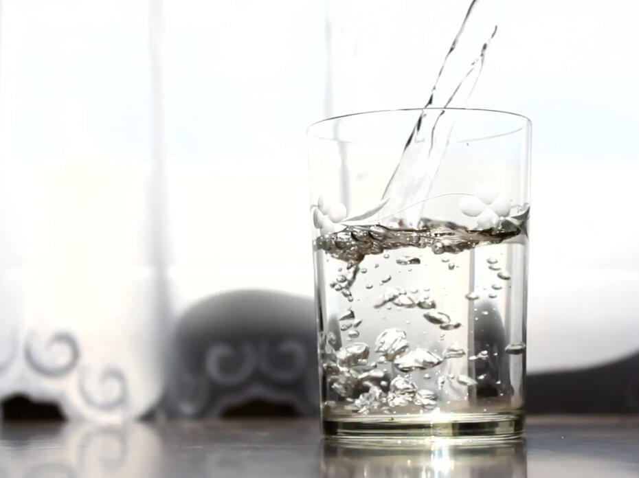 A person off-camera pours water into a glass.