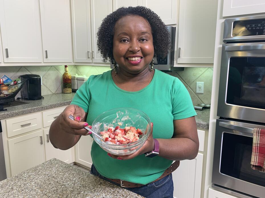 A woman holds a bowl of berries and banana cream.