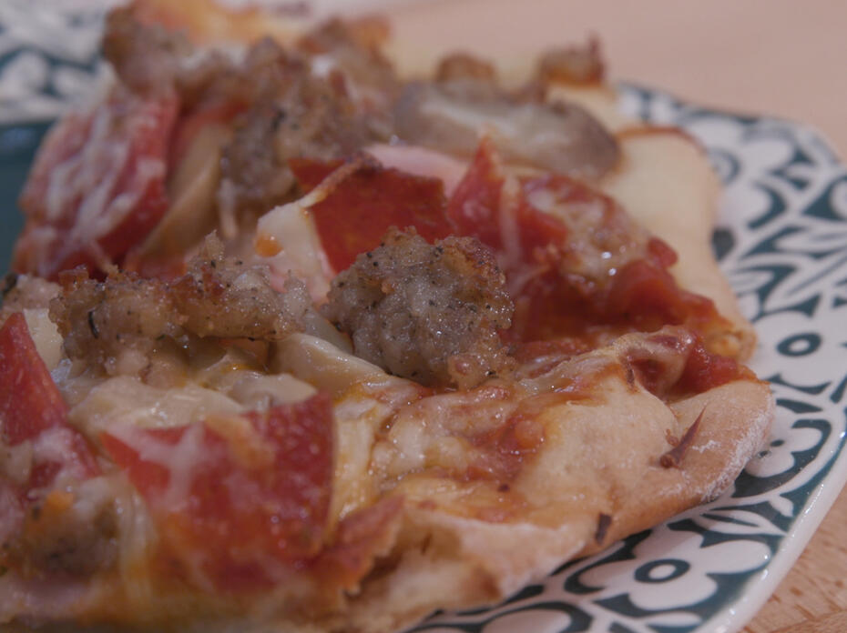 homemade meat pizza on a teal plate with white floral border