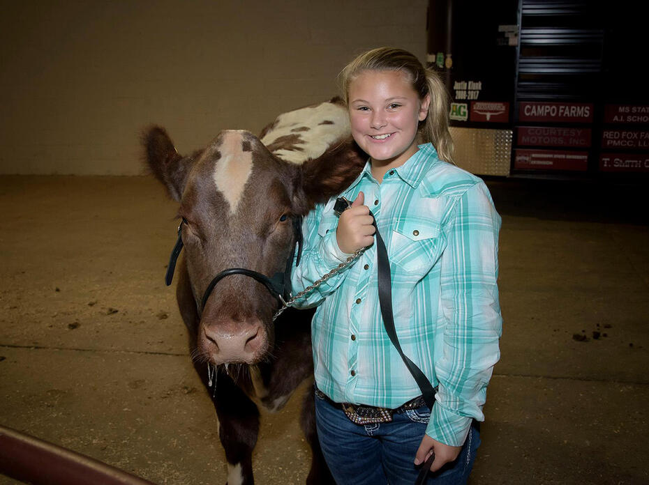 A young girl stands beside a cow at the Mississippi State Fair.