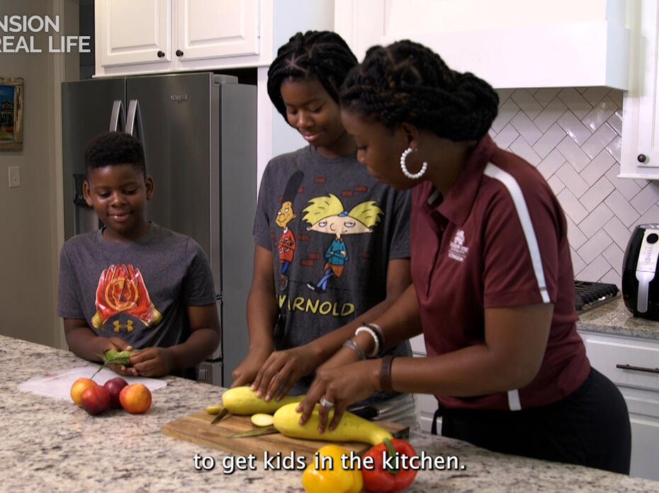 A woman and two children slice vegetables