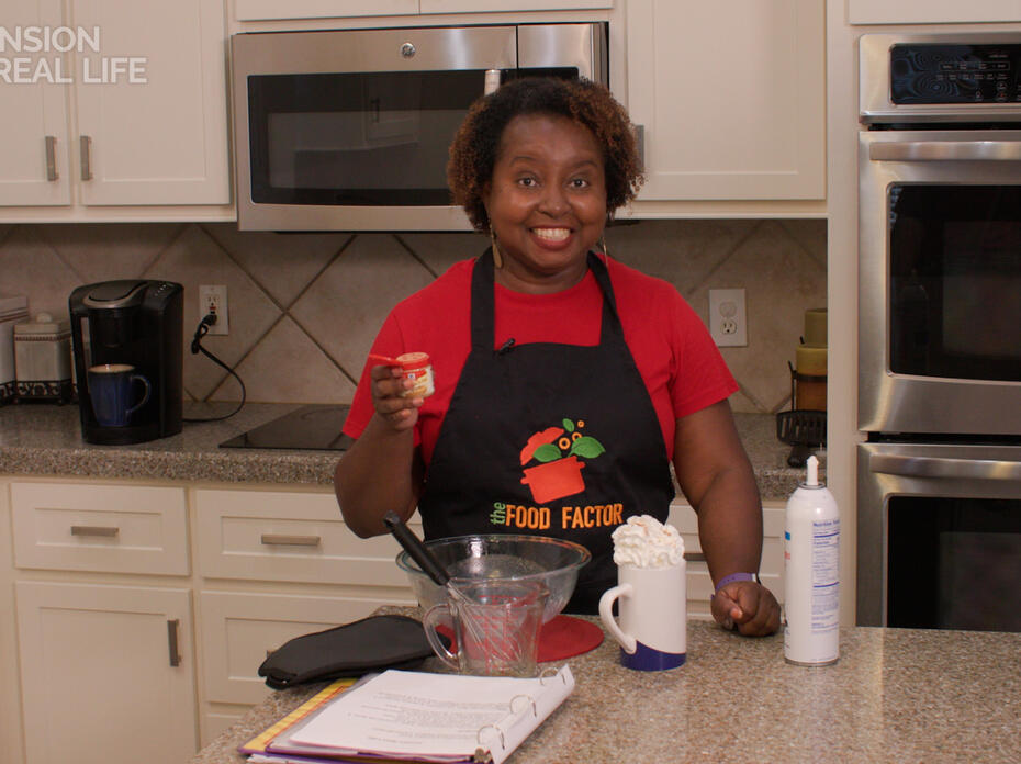 A woman stands at a kitchen counter with a latte.