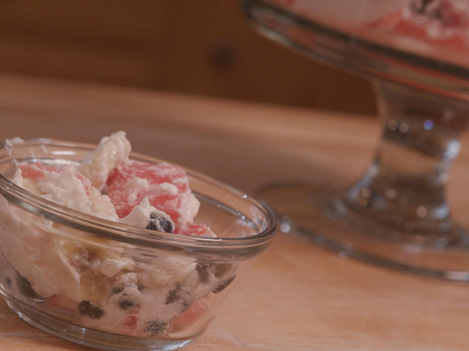 fruit salad with whipped topping in a clear glass bowl
