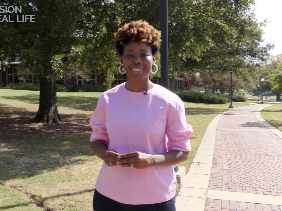 A woman stands on a sidewalk.
