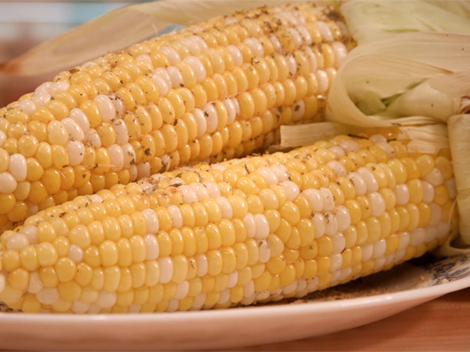 Two ears of seasoned grilled corn on a platter. 