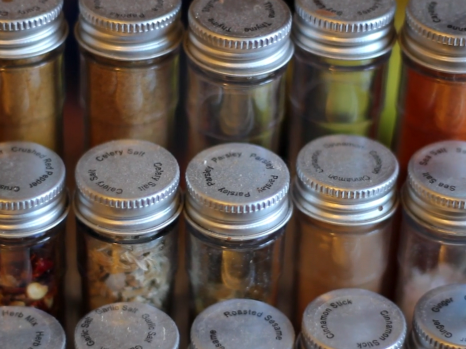 Rows of spices in clear jars with silver tops. 