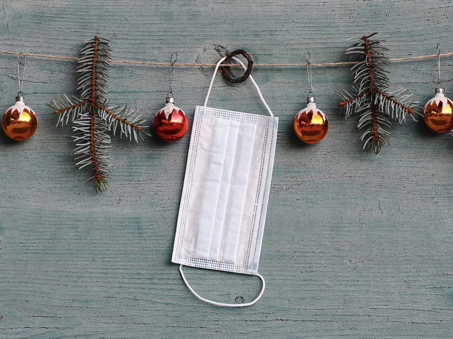 A white mask hanging on Christmas garland.