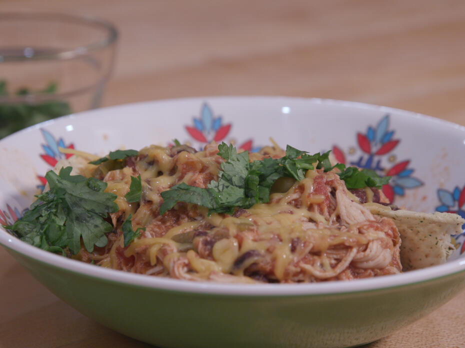 Chicken tortilla soup in a colorful bowl with a small glass bowl of cilantro in the background
