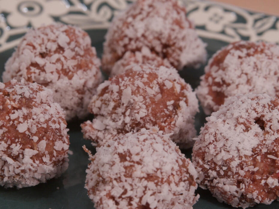 Strawberry cookie dough balls coated in coconut on a plate
