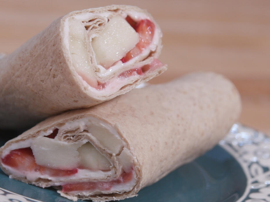 strawberry-banana cheesecake wrap cut in half and displayed on a decorative plate