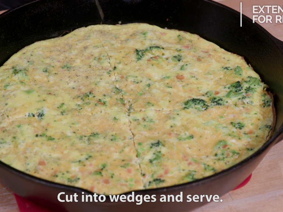  A mixture of small broccoli florets, diced carrots, eggs and cheese baked as a frittata in a large black cast-iron skillet.