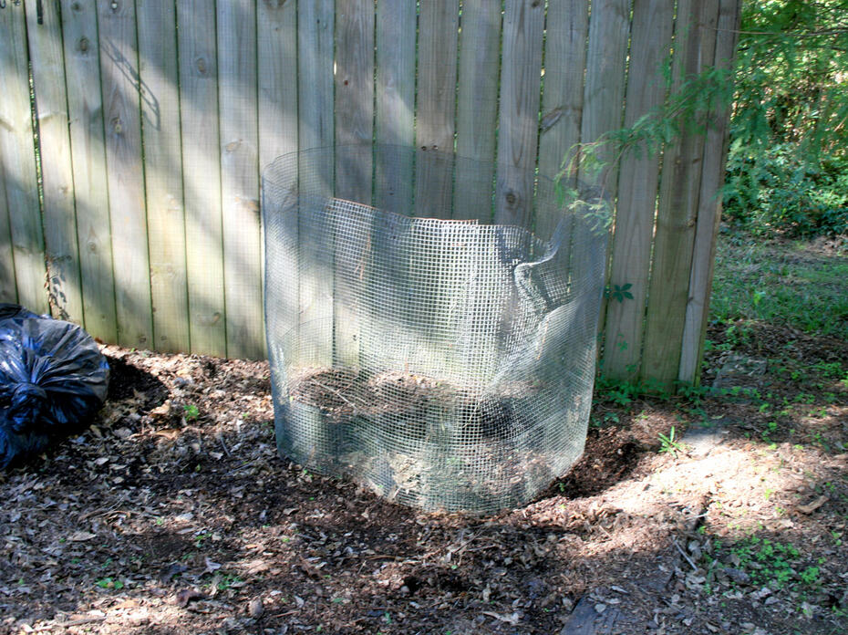 A piece of hardware cloth encircles a small, layered pile of organic waste.