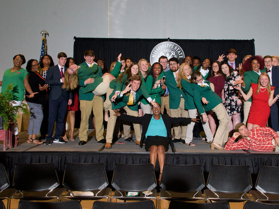 A group of teenagers posing on a stage. 
