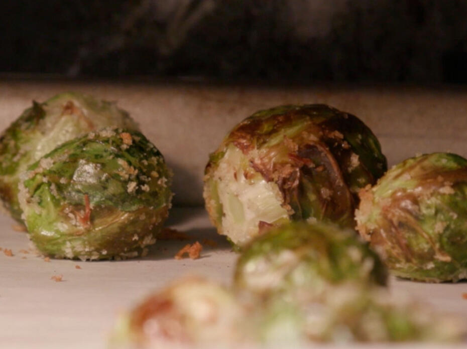 Close-up of roasted Brussels sprouts coated with Panko breadcrumbs on a sheet pan covered with parchment paper. 