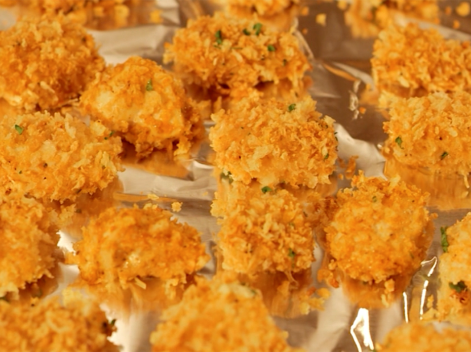 Chicken nuggets coated in golden brown panko breadcrumbs on an aluminum-foil lined baking sheet. 