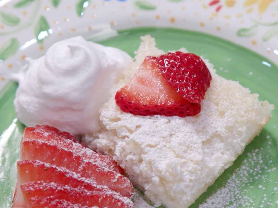 Angel food cake with strawberries, cool whip, and strawberries on a green plate.