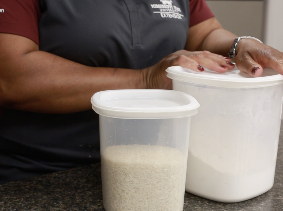 Two partially filled canisters contain rice and flour sit on a speckled black countertop.