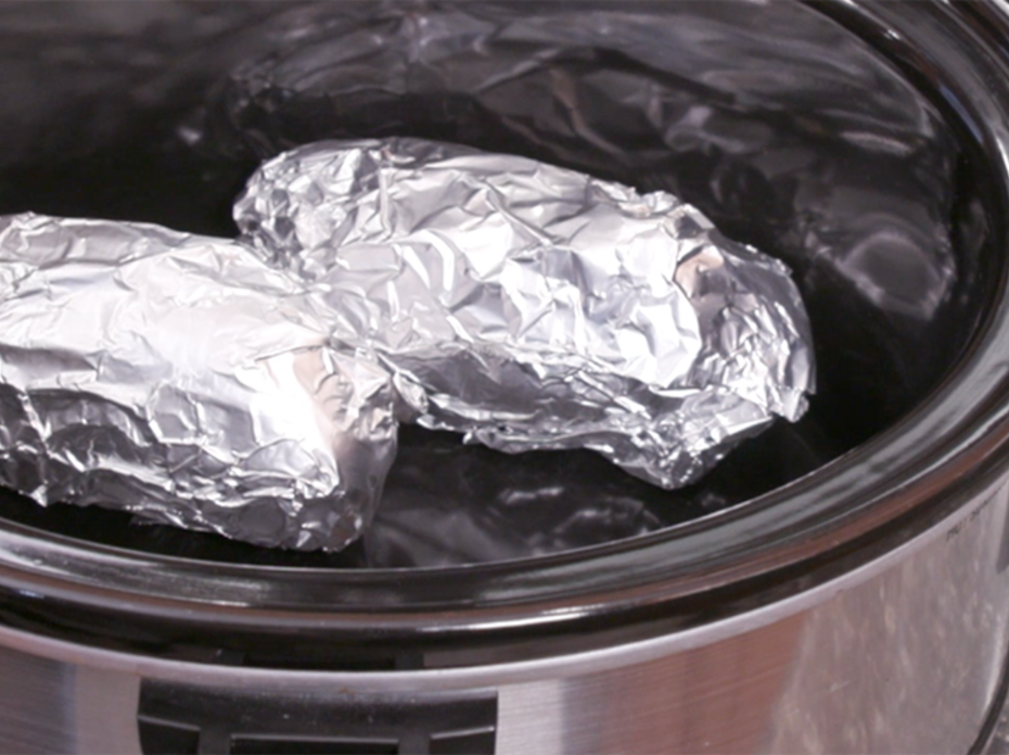 Foil wrapped potatoes in a slow cooker.