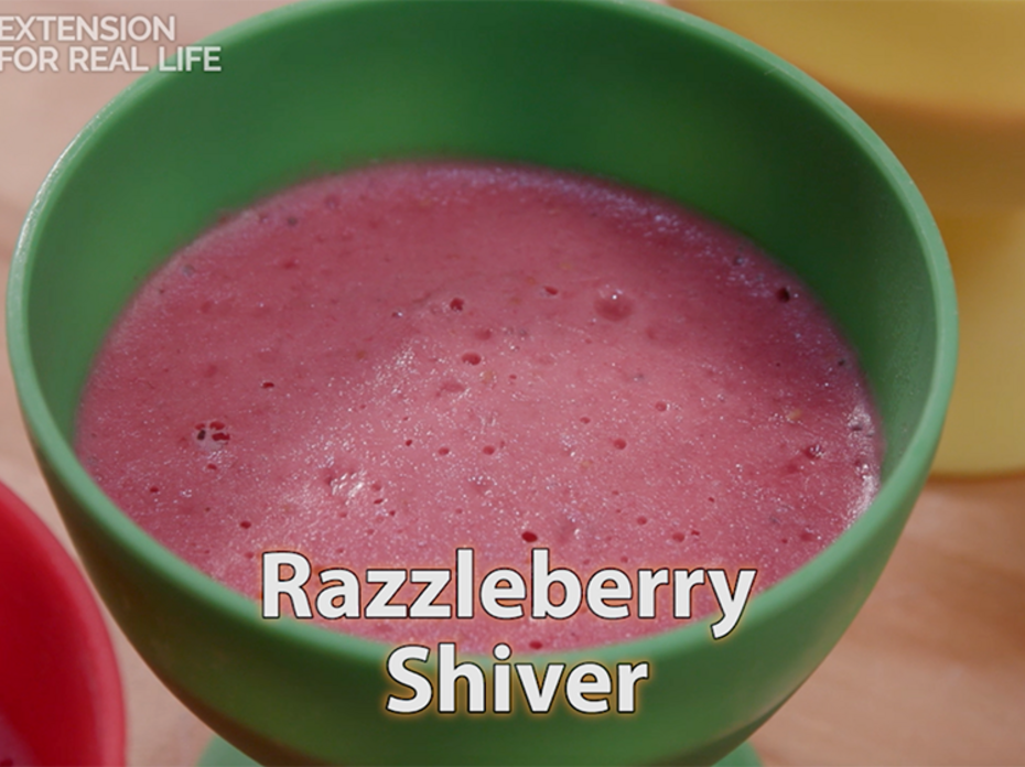 A pink blended raspberry dessert in a green cup.