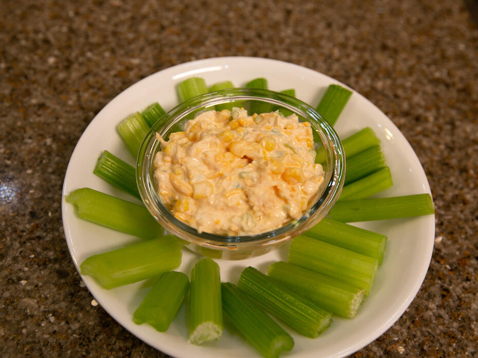 a bowl of Buffalo Chicken Dip stis on a plate surrounded by celery stalks