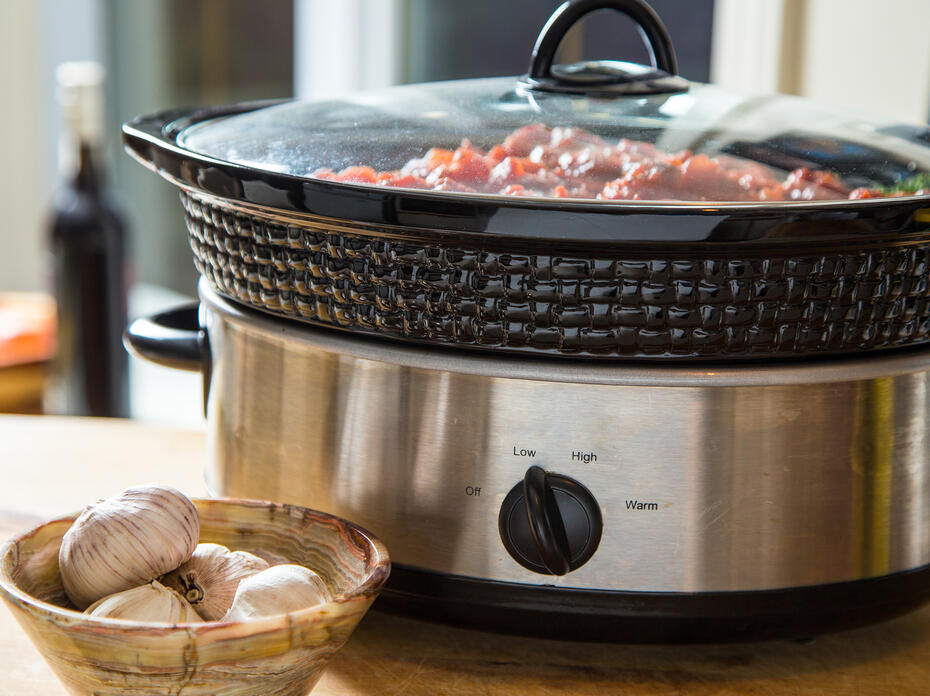 A slow cooker filled with a meal sits on a counter.