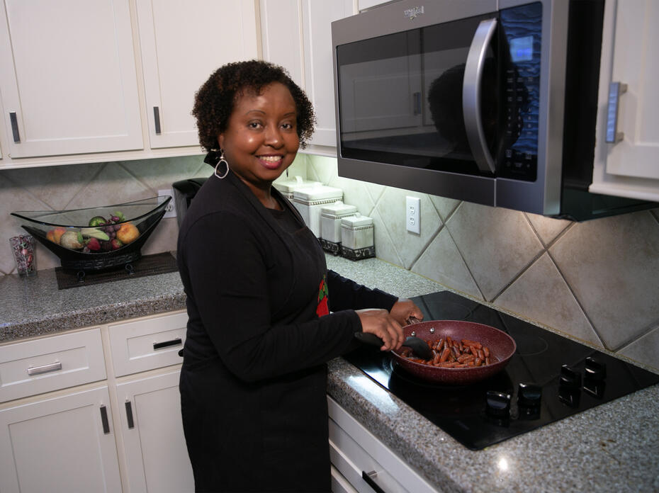 A woman stirs balsamic glazed carrots cooking on the stove.