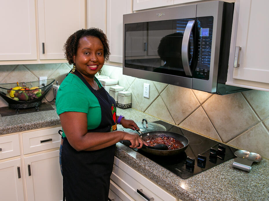 A woman stirs cranberry turkey meatballs cooking on the stove.