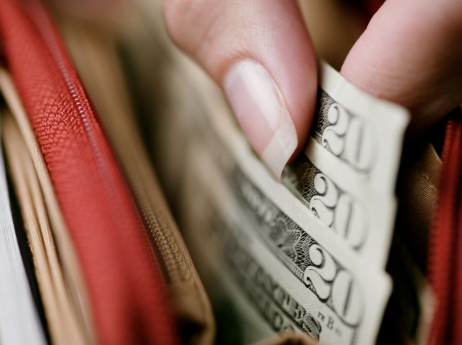 a closeup of a person taking $20 dollar bills out of a wallet