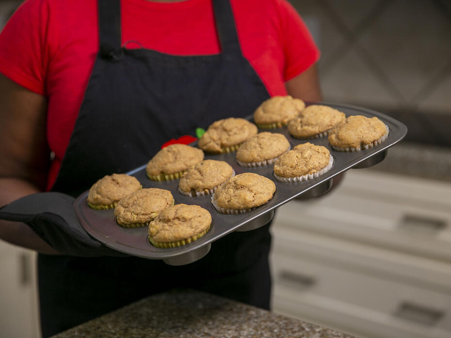 A woman holds a muffin tin full of Peanut Butter Muffins.