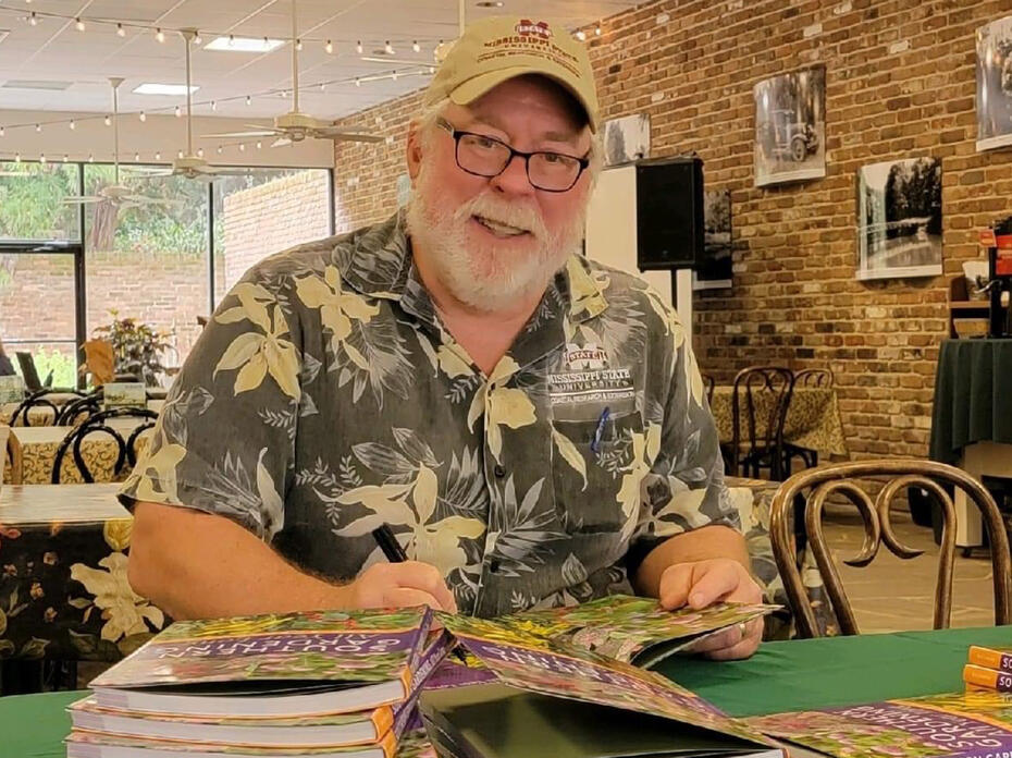 A man sits at a table with books.