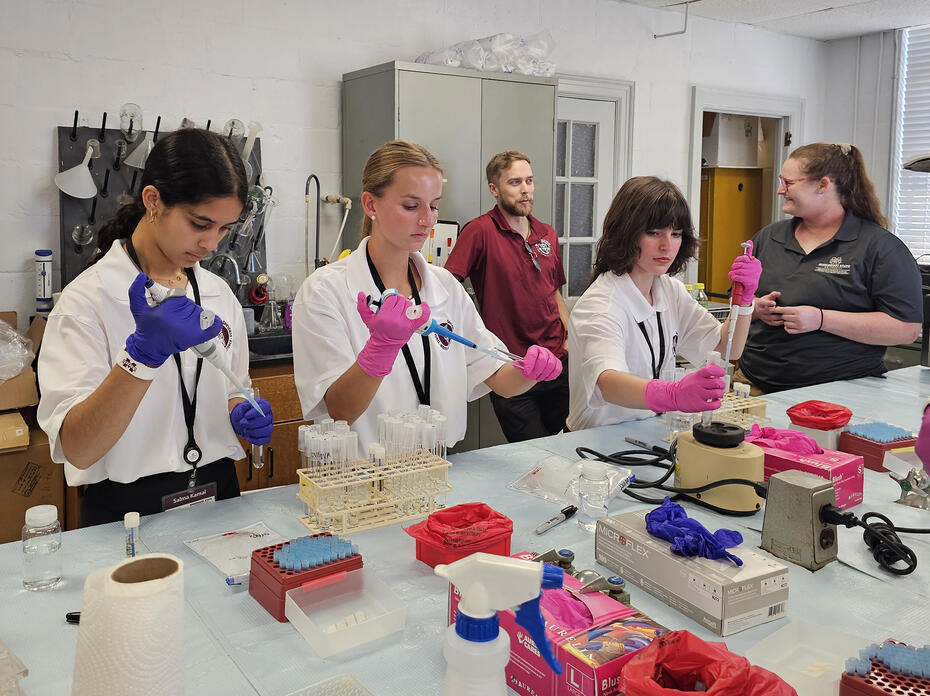A group of young people use lab equipment in a classroom.