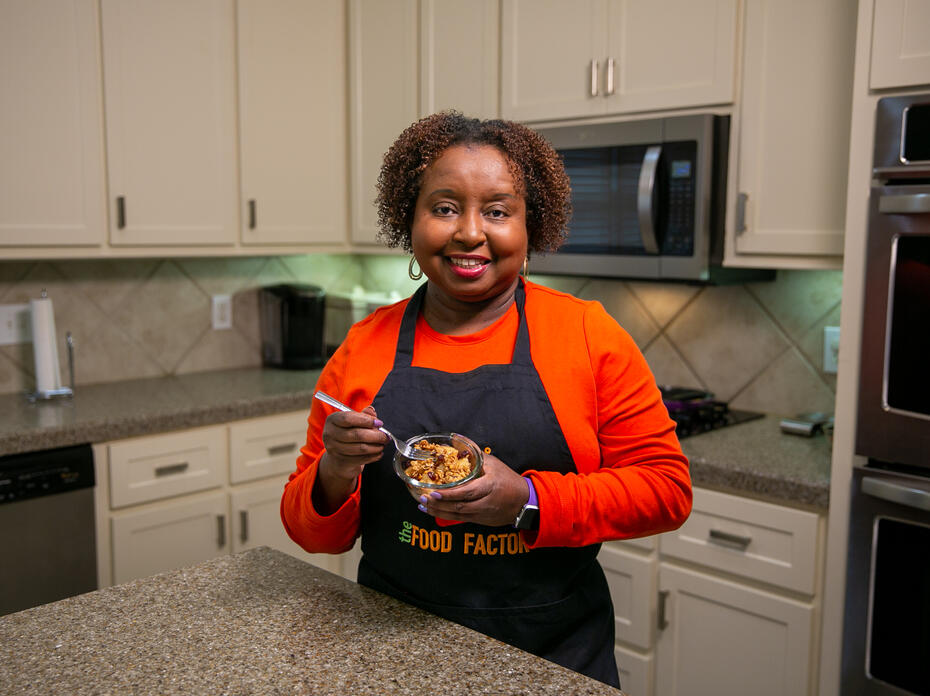 A woman stands in a kitchen and holds a bowl of Cinnamon Fried Pineapple