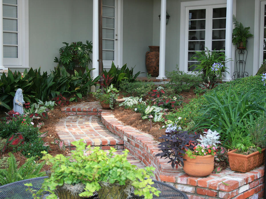 A curving brick walkway lined with plants leads up to a porch.